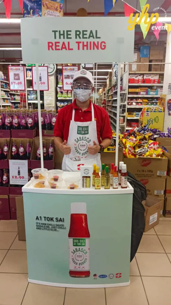 Sabasco A1 Tok Sai East Malaysia Roadshow 3 Male promoter standing at a Sabasco chili sauce sampling booth inside a grocery store aisle with product tasters in kota Kinabalu supermarket