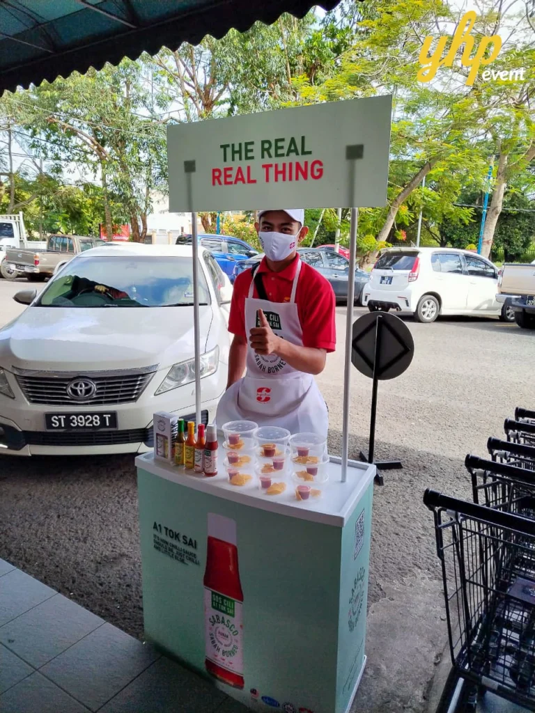 Sabasco A1 Tok Sai East Malaysia Roadshow 6 Outdoor brand activation booth for Sabasco chili sauce with a promoter standing next to stacked shopping carts