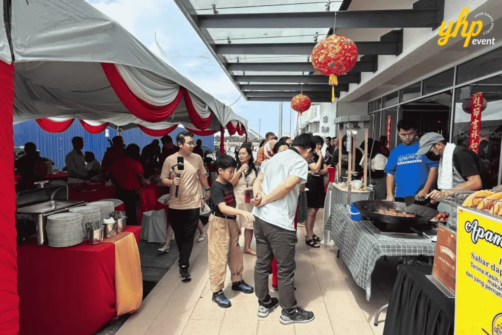 Guests queue beside a live cooking station and buffet tent during a daytime festive gathering at the sales gallery of Aeropod. 