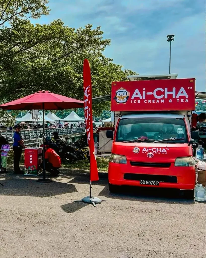 Celebrating Ai Cha’s “Love You 300x” Campaign – Brewing Across Sabah! 5 Red Ai-CHA mobile kiosk set up outdoors near tents and shaded seating in outskirt Sabah