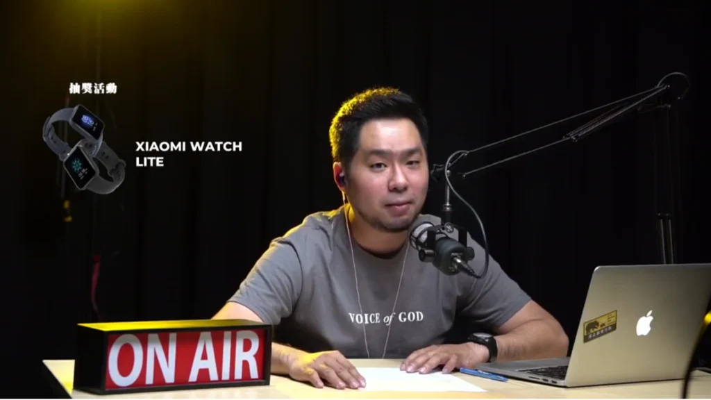 Close-up of host with microphone and laptop during the live stream launch of new Mandarin worship music album