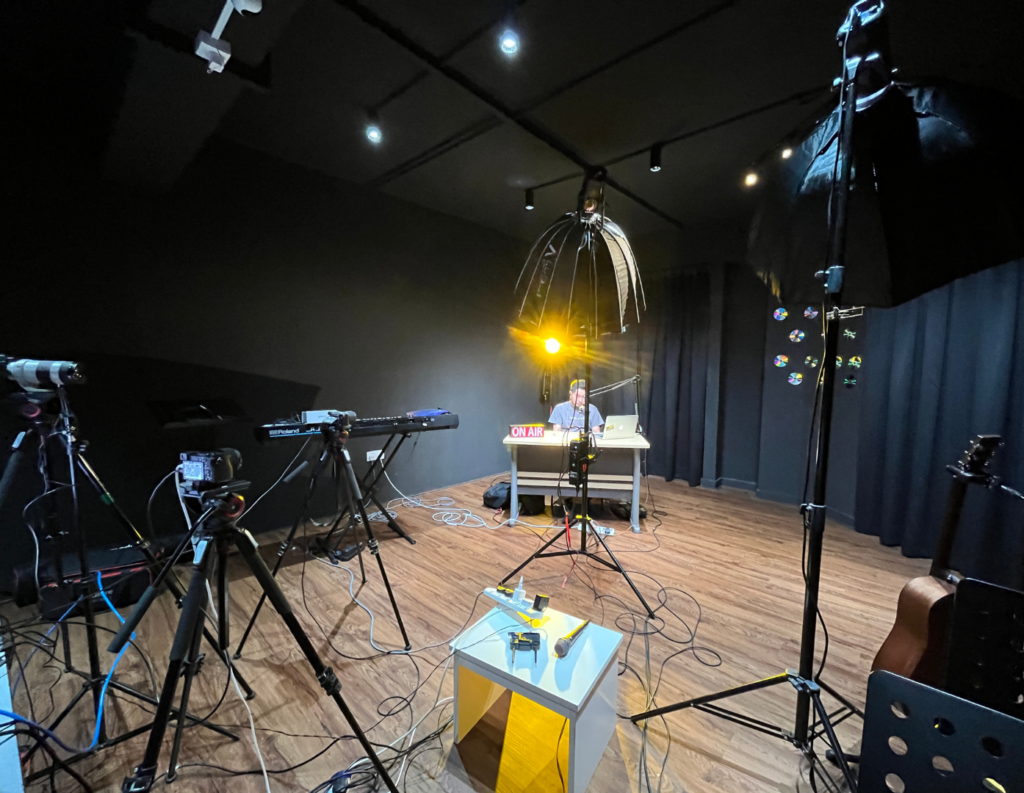 Professional studio setup with cameras, lighting, and Roland keyboard for recording Mandarin worship music album