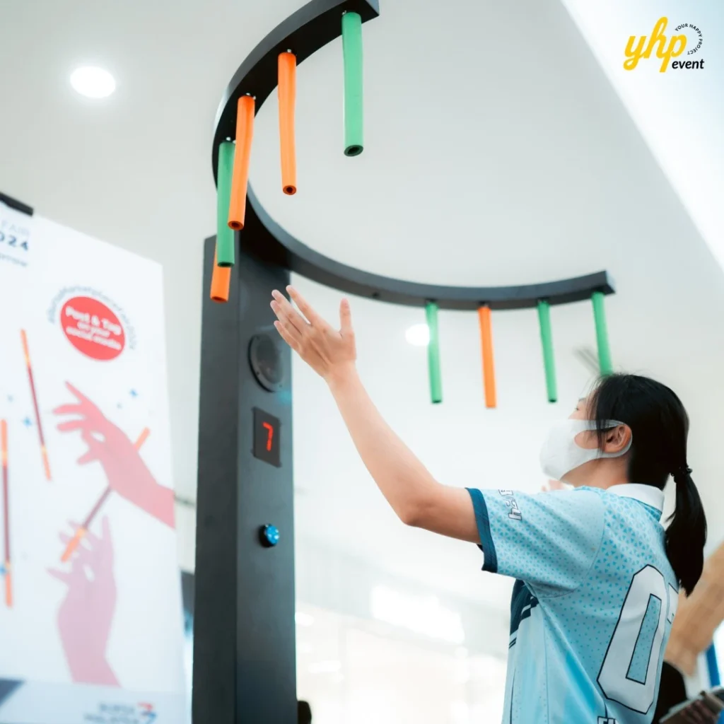 Bursa Marketplace Fair 2024: Invest Today, Harvest Tomorrow 10 Participant playing a reaction speed game with hanging rods at the Bursa Marketplace Fair 2024 activity