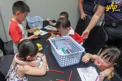 Young children sitting at a table coloring CoComelon themed activity sheets