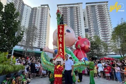 A traditional Chinese God of Fortune mascot and green dragon performance in front of a large crowd