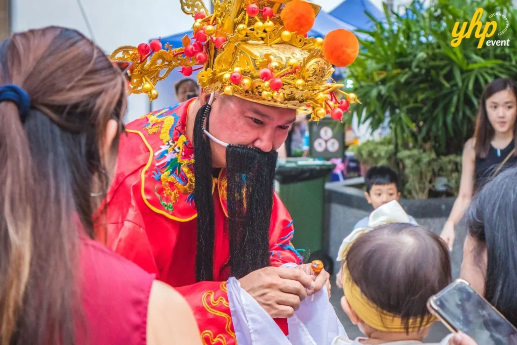 The Chinese God of Fortune mascot handing out treats to a young child during a cultural celebration