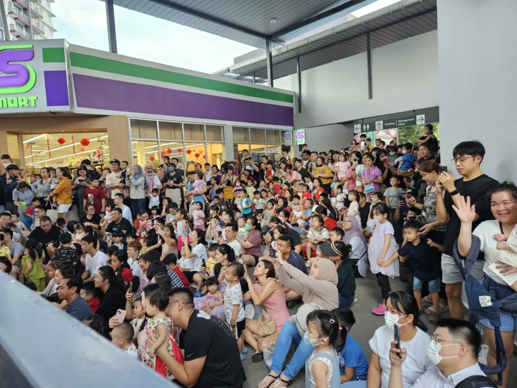A massive Sabahan crowd of families and toddlers sitting on the floor waiting for a live stage performance