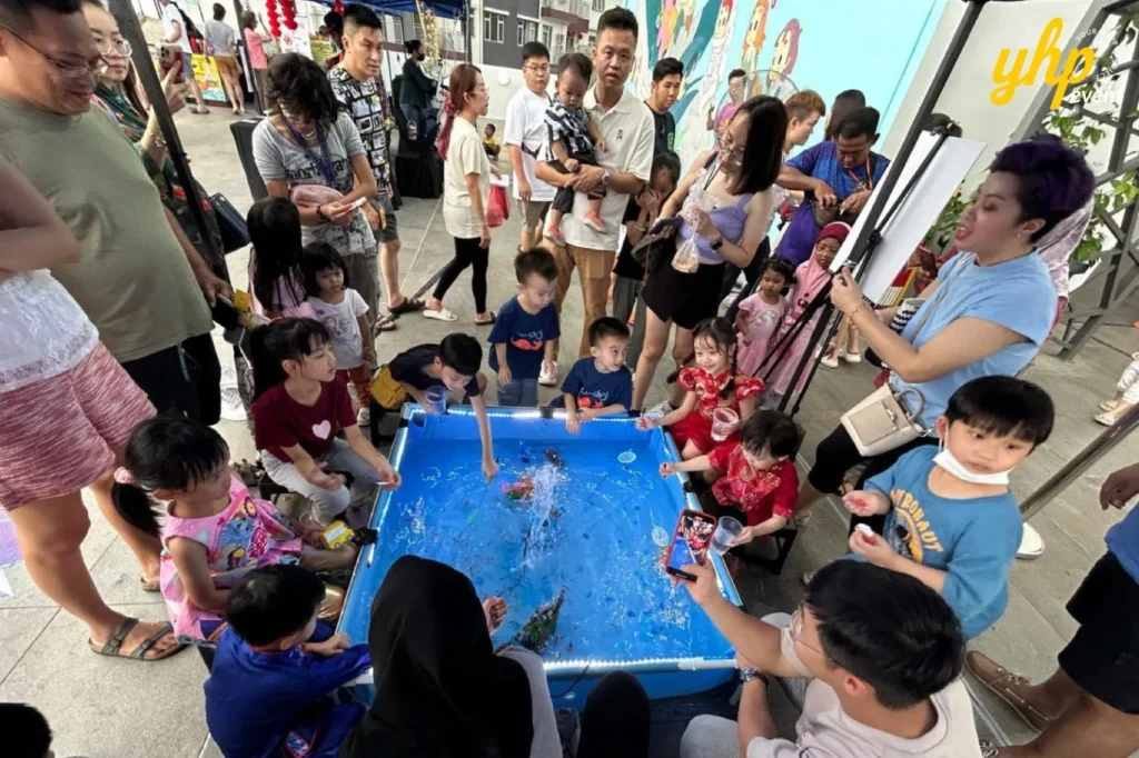 A group of children gathered around a fish pond activity at a CoComelon event