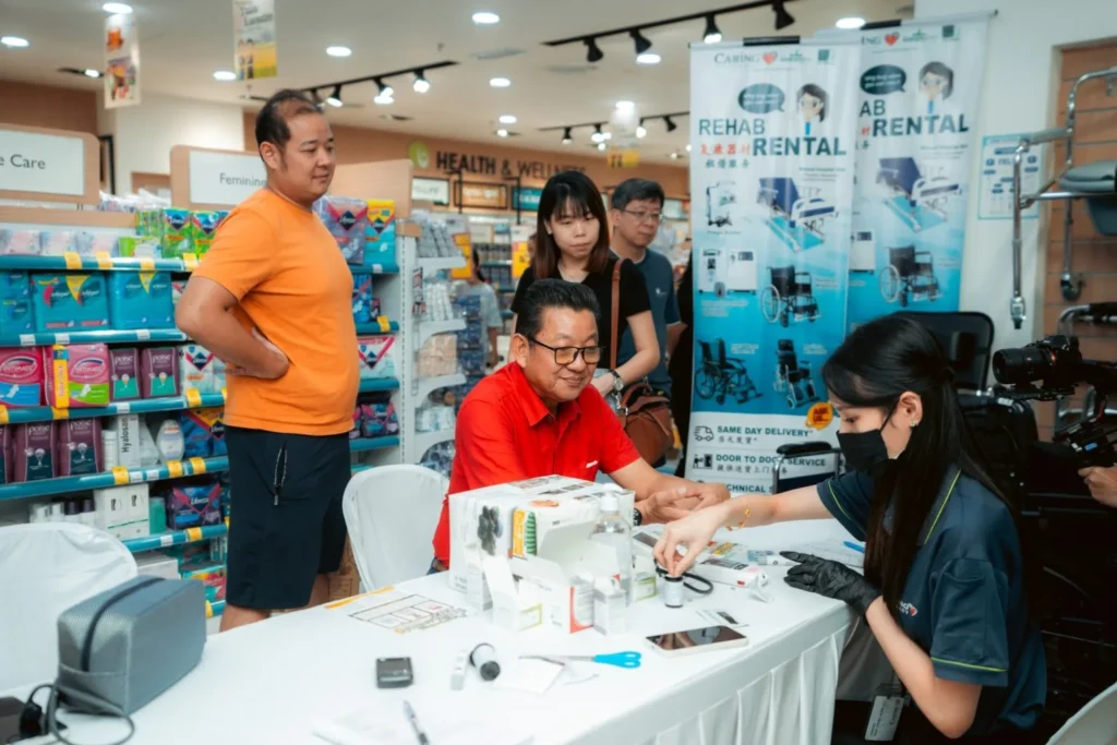 Embrace the Essence of Caring Pharmacy #Promosi Tadau Kaamatan 5 Customer receiving a medical consultation at a Caring Pharmacy rehab and rental service booth in the store
