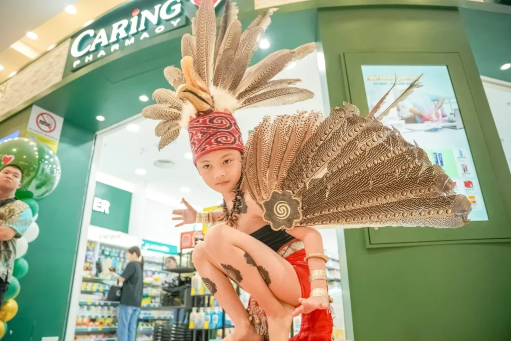 Child in traditional feathered costume posing at Caring Pharmacy entrance
