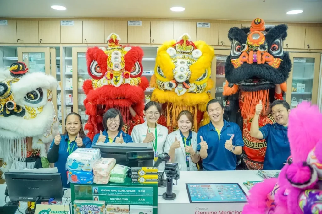 Caring Pharmacy Kaamatan & Gawai Campaign Launch 6 Caring Pharmacy Kuching employees give thumbs up beside lion dancers inside the store