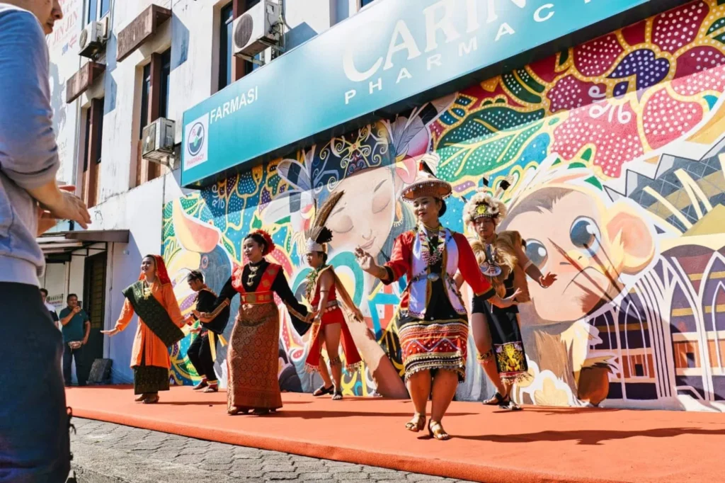 Caring Pharmacy Mural Unveiling l Kota Sentosa Kuching 3 Sarawak Traditional dancers perform outside Caring Pharmacy in front of a vibrant mural and red carpet stage
