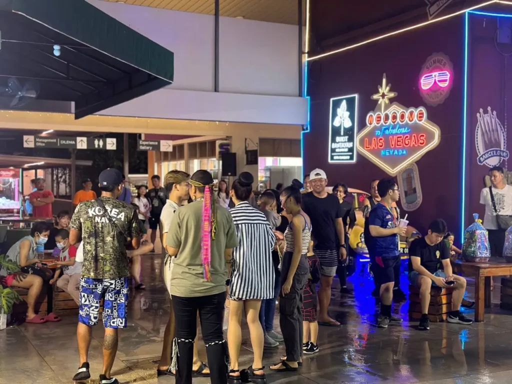 Curve25 Olumes Land : Kaamatan Celebration in Kota Kinabalu 3 Night scene at Bukit Bantayan Residences featuring a neon Las Vegas sign and people