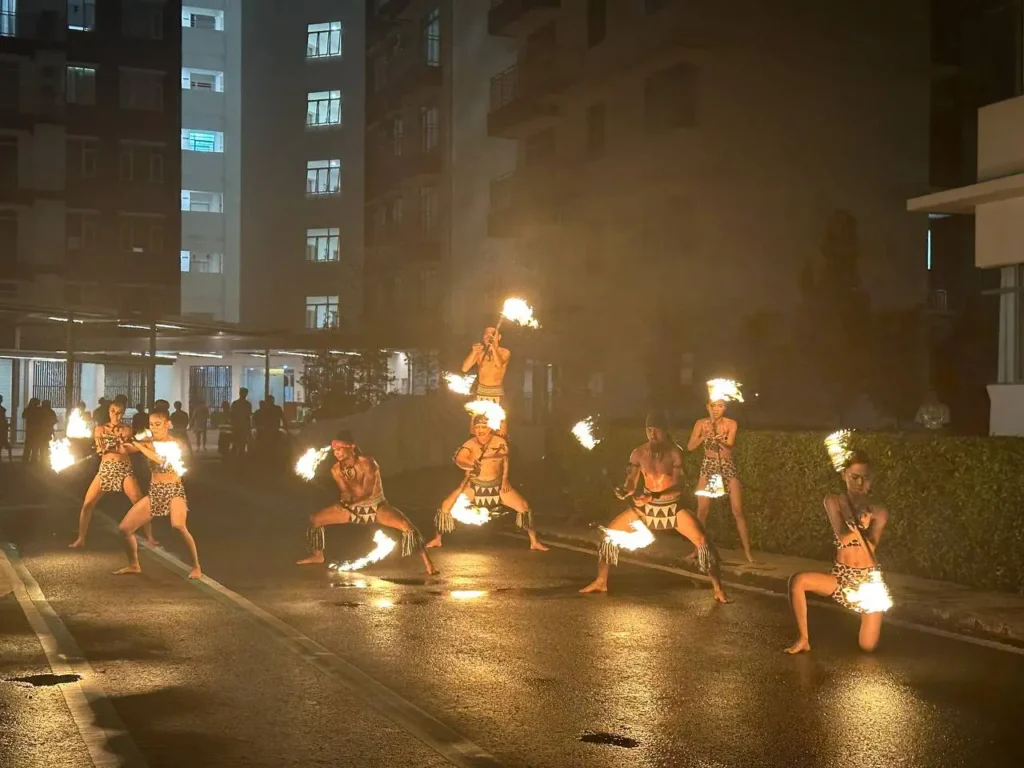 Curve25 Olumes Land : Kaamatan Celebration in Kota Kinabalu 4 Performers in tribal attire execute a dramatic fire dance routine on a wet street at night