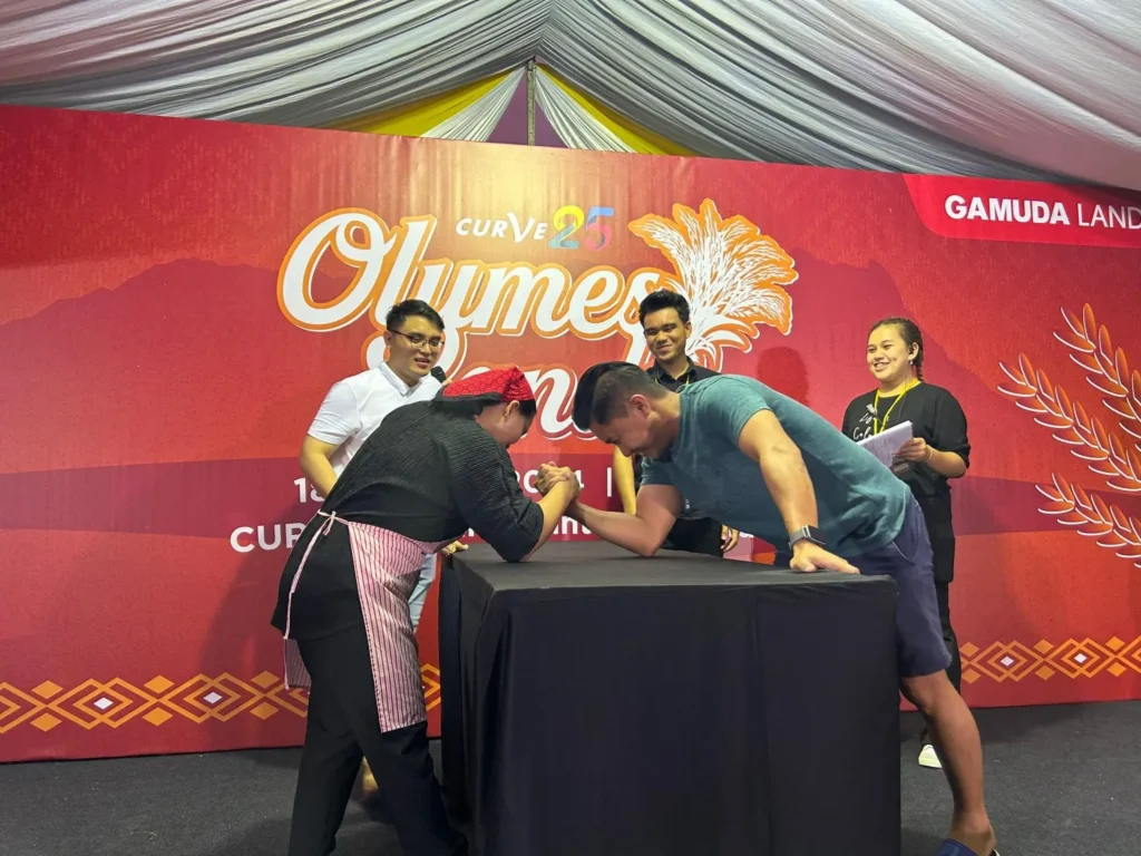 Curve25 Olumes Land : Kaamatan Celebration in Kota Kinabalu 5 Two people engaged in a competitive arm wrestling match on a stage