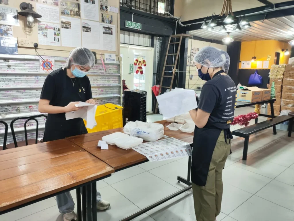 Two workers preparing food containers