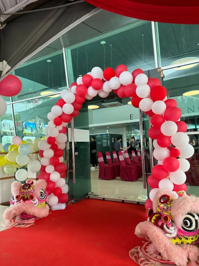 Red and white balloon arch entrance with lion dance heads at the E Residence property development gallery