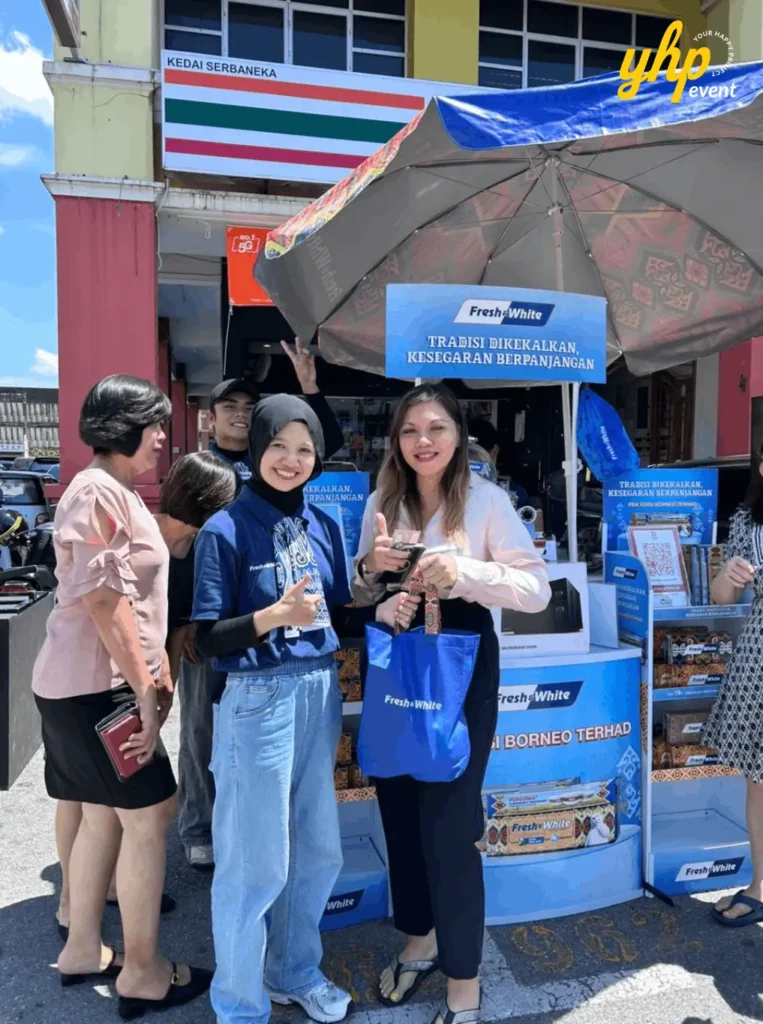 Fresh & White Borneo Edition: Out-of-Home Activation Across Sabah & Sarawak 3 Fresh and White booth visitors smile with giveaway bag beneath umbrella stand outside shopfront during street event