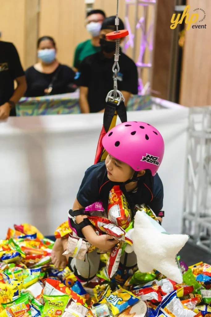 Celebrating the Grand Launch of Curve25 14 A young girl in a pink helmet playing the human claw machine to win snacks