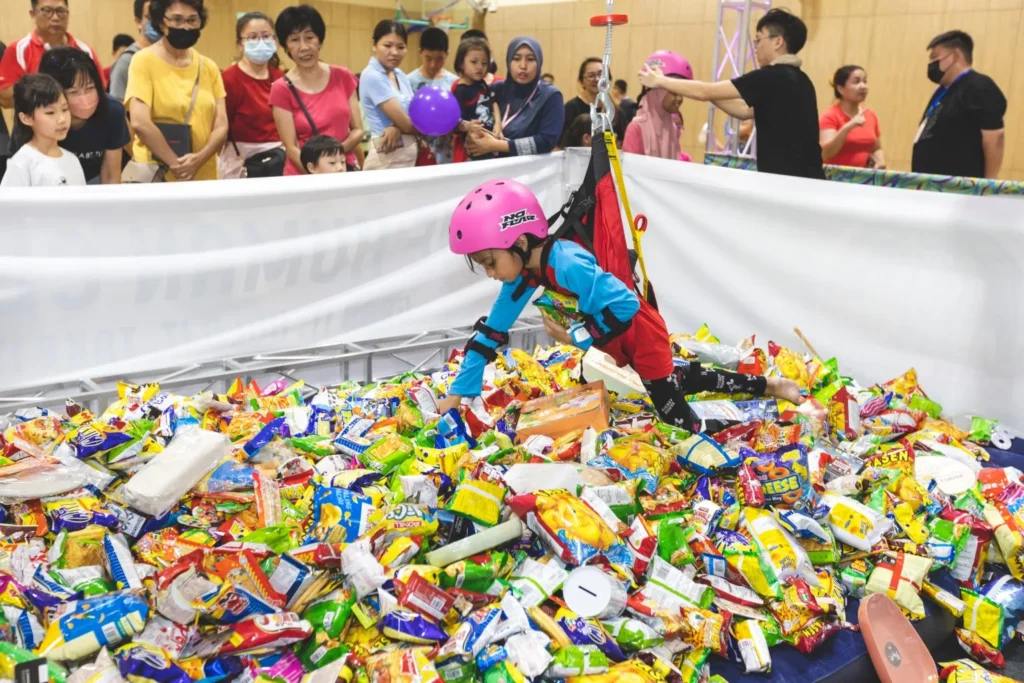 Celebrating the Grand Launch of Curve25 15 A child suspended in a harness dives into a large pit of snacks