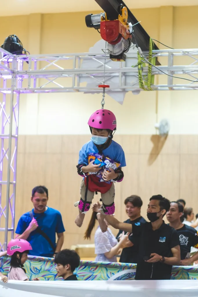 Celebrating the Grand Launch of Curve25 16 A young boy wearing a mask and helmet being lowered into the snack pit