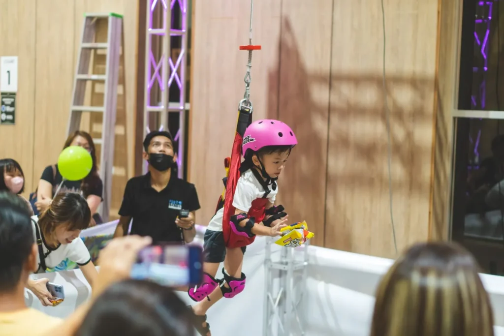 Celebrating the Grand Launch of Curve25 17 A toddler in a safety harness participating in the human claw machine activity