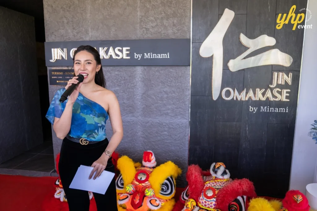 Grand Launching of JIN Omakase: A Culinary Extravaganza in Kota Kinabalu 6 Event host speaking into a microphone during the Jin Omakase by Minami opening ceremony with lion dance heads nearby