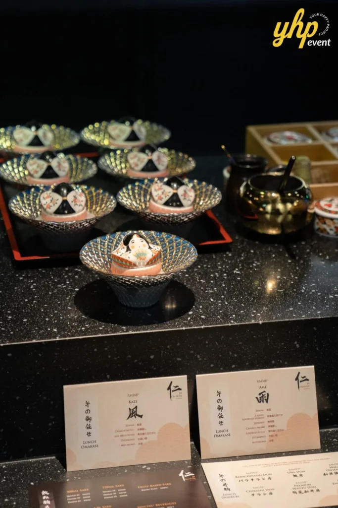 Grand Launching of JIN Omakase: A Culinary Extravaganza in Kota Kinabalu 9 Elegant Japanese chawanmushi bowls shaped like traditional dolls on a black counter