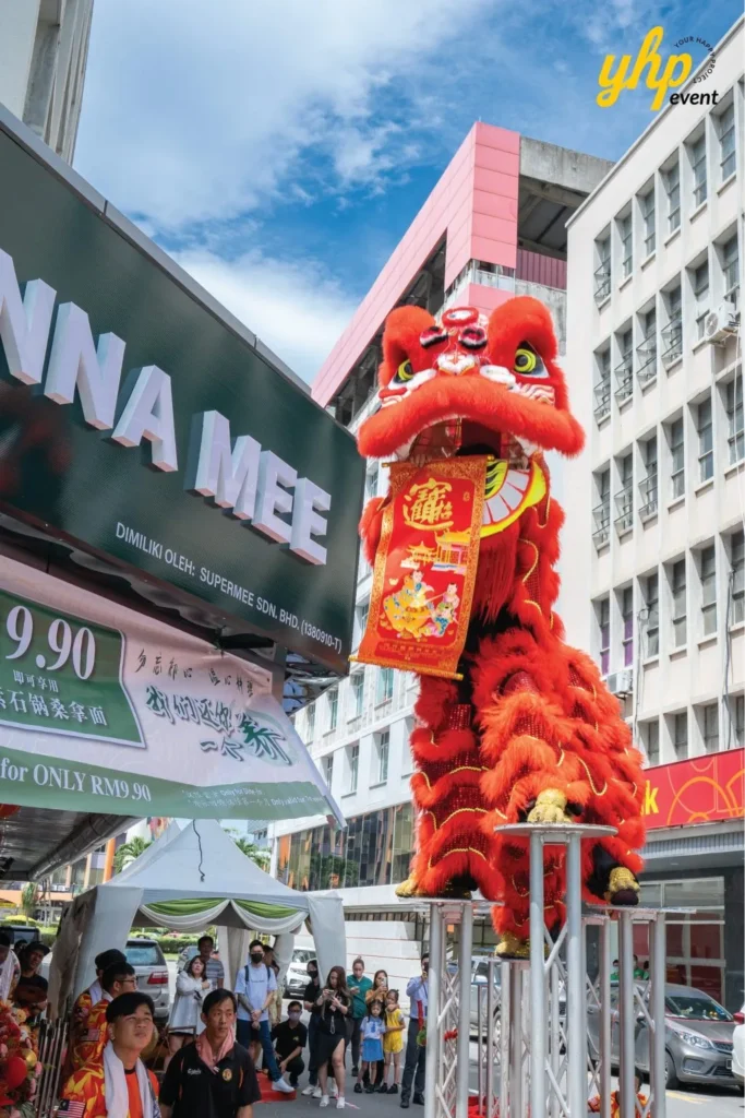 Grand Opening of Young Sanna Mee in Sabah - Enjoy Delicious and Healthy Noodles 3 Red lion dance performer on tall metal poles during the Young Sanna Mee grand opening event outdoors