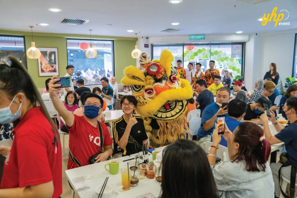 Grand Opening of Young Sanna Mee in Sabah - Enjoy Delicious and Healthy Noodles 4 Customers taking photos of a yellow lion dancer inside the crowded Young Sanna Mee dining area