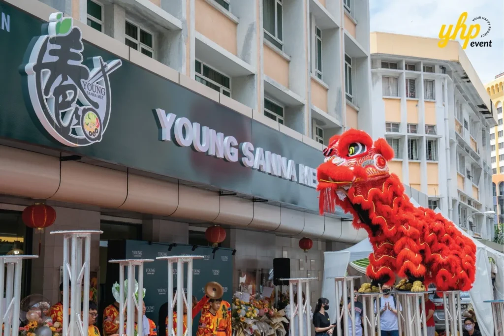 Grand Opening of Young Sanna Mee in Sabah - Enjoy Delicious and Healthy Noodles 9 Red lion dance performer balancing on high metal poles in front of the Young Sanna Mee restaurant sign