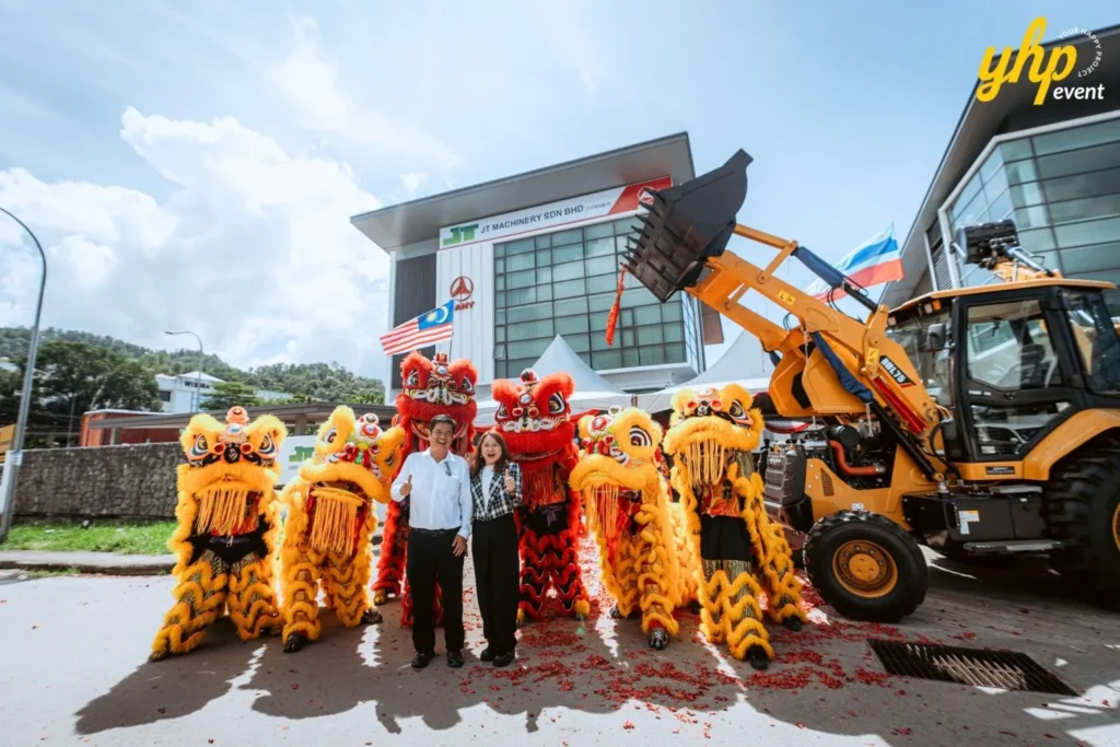 JT Machinery Office Launching 4 Group photo of JT Machinery Sdn Bhd staff and lion dancers in front of a SANY backhoe loader