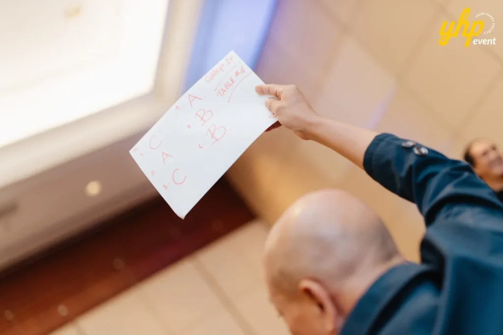 Participant holding up a handwritten quiz answer sheet during a corporate team building activity