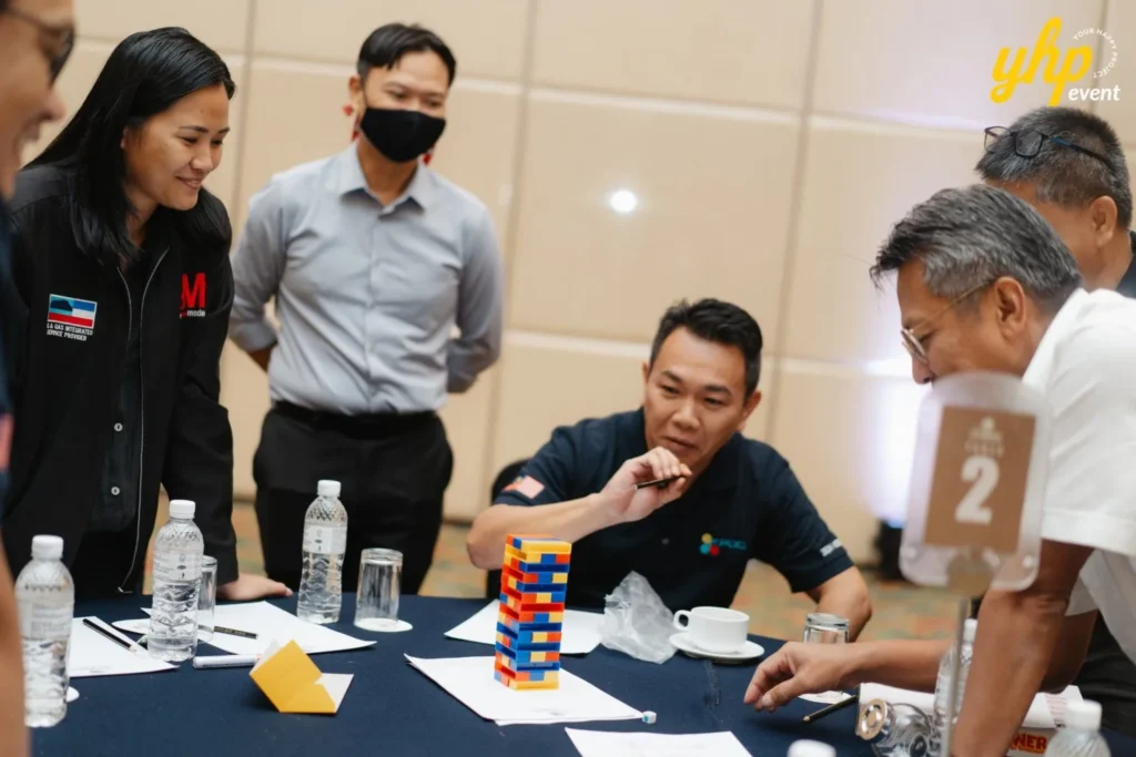 Coworkers collaborating on a Jenga style tower game at a business event table