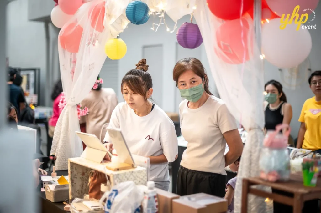 Magical Mid Autumn Gathering in Curve25 16 Two women managing a decorated booth at a Mid-Autumn Festival bazaar featuring lanterns and fairy lights