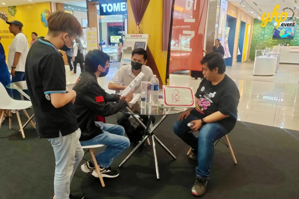 Experience Innovation and Comfort at the Nissan Roadshow 2 Nissan sales representative showing car brochure to customers at a mall roadshow booth display event