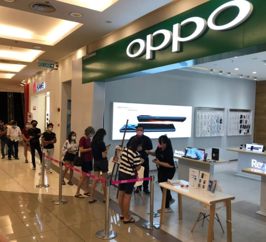 A queue of customers wearing face masks waiting outside an OPPO store in a shopping mall for a new product launch