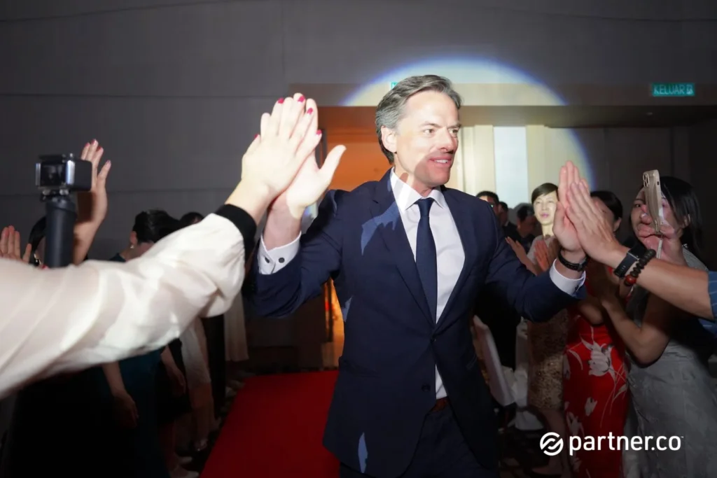 Unleashing the Future of Business: Partner.Co's Star Partner Business Conference & Award Night 8 Male executive in a navy suit giving high-fives to enthusiastic attendees at a Partner.Co brand event