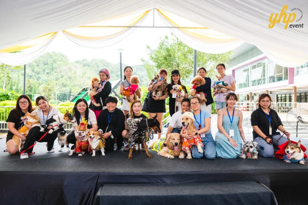 Group of pet owners posing with their dressed-up dogs and cats on a stage