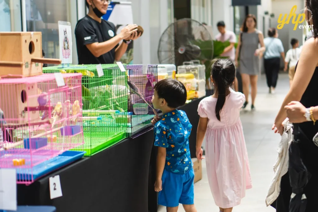 Young children looking at colorful bird cages and parrots