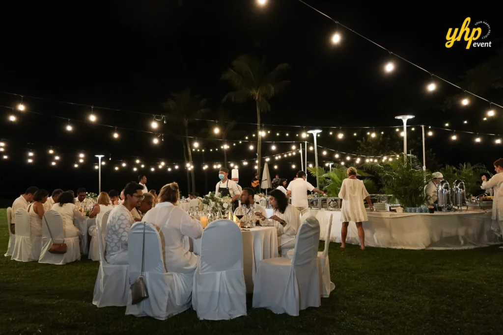 Shangrila rasa ria Large group of people dining at round tables for a formal white theme dinner party on a lawn at Shangrila Rasa Ria Hotel