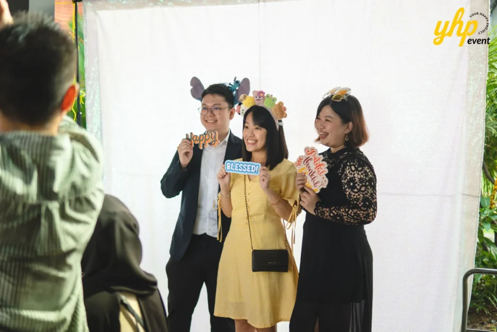 Happy guests posing with fun props at a photo booth during a corporate gala dinner party celebration