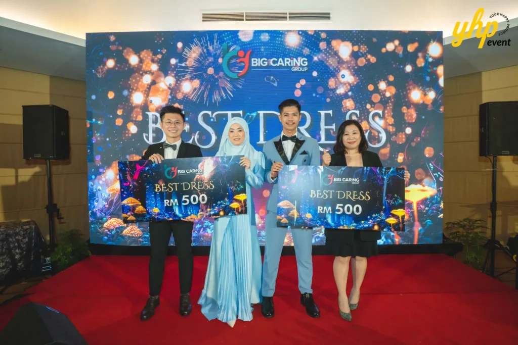 Best Dress award winners holding prize vouchers on stage at the Big Caring Group corporate event