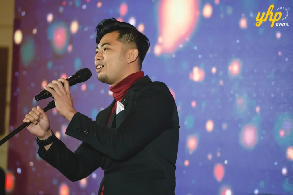 Man holding microphone in front of a digital screen at a corporate gala dinner