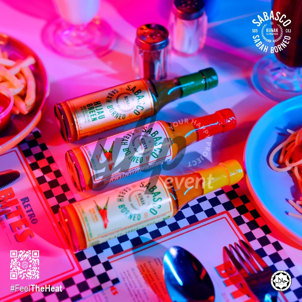 The Local Sabah Chili Sauce Brand That’s Heating Up 24 Three Sabasco Sabah Borneo chili sauce bottles on retro diner placemats beside pasta and fries under neon lights