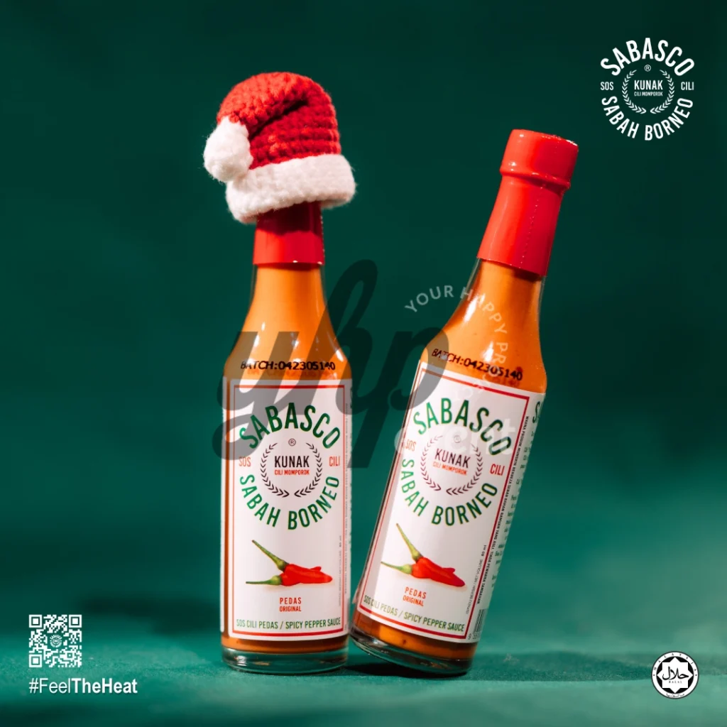 The Local Sabah Chili Sauce Brand That’s Heating Up 31 Two Sabasco Sabah Borneo original chili sauce bottles on a green backdrop, one topped with a tiny Santa hat