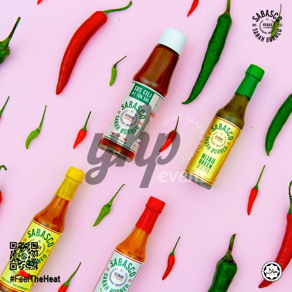 The Local Sabah Chili Sauce Brand That’s Heating Up 37 Flat lay of Sabasco Sabah Borneo chili sauce bottles with scattered red and green chilies on a pink background