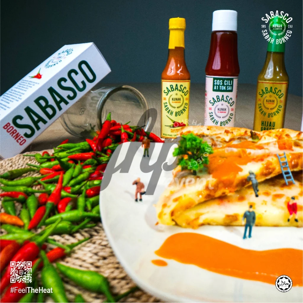 The Local Sabah Chili Sauce Brand That’s Heating Up 38 Sabasco Sabah Borneo chili sauce bottles with pizza slices, fresh chilies, and miniature figures on a white plate