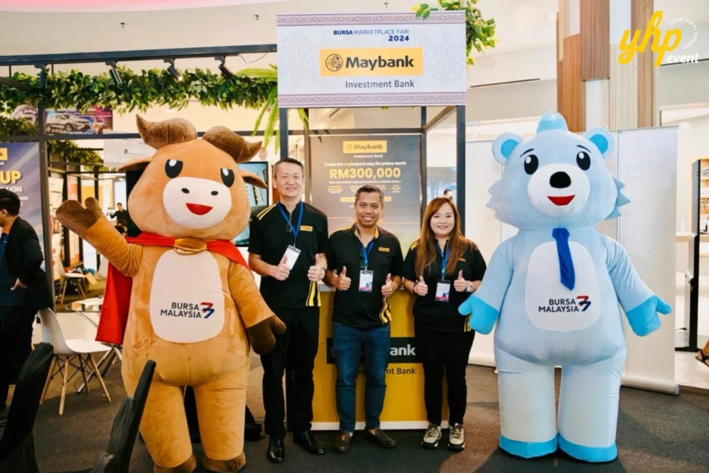 Bursa Marketplace Fair 2024: Sarawak Edition 13 Maybank Investment Bank staff posing with Bursa Malaysia bull and bear mascots at the 2024 fair