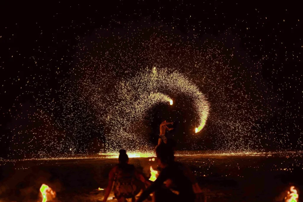 Spark Fest Carnival l Karambunai Hotel 10 Sabah popular Fire performer creates a wide arc of sparks on the beach at night while seated spectators watch nearby